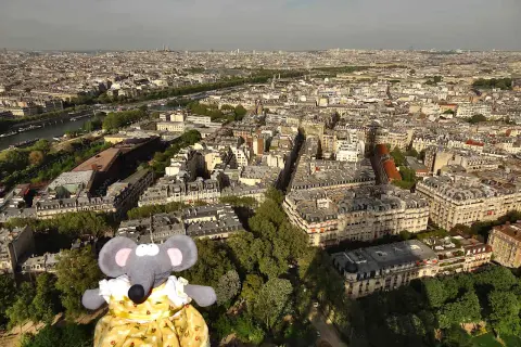 Une souris en robe jaune admire Paris depuis le sommet de la Tour Eiffel.