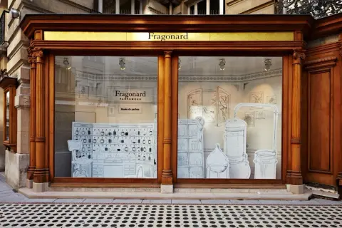 Vitrine du musée du parfum Fragonard, avec des illustrations de flacons, d'alambics et de mobilier d'apothicaire.