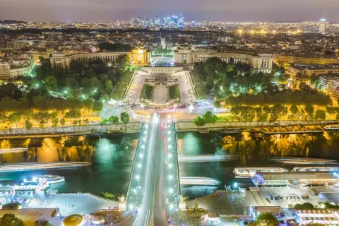 Paris la nuit, le scintillement de la Tour Eiffel se reflète sur la Seine, illuminant la ville.