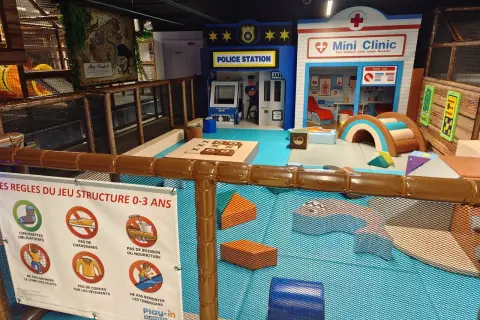 Aire de jeu pour enfants à Paris avec une station de police, une mini-clinique et des structures ludiques. Sept carrés colorés pour le jeu.