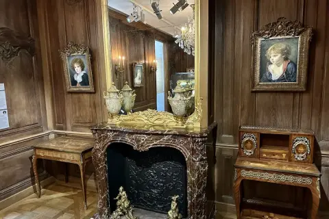 Un salon d'époque avec des portraits d'enfants, une cheminée en marbre et des meubles anciens. On imagine le cognacq jay dégusté dans ce cadre.