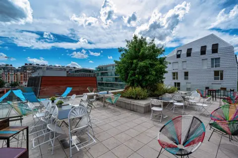Terrasse ensoleillée avec chaises colorées et tables, un lieu idéal pour la maison de la conversation.