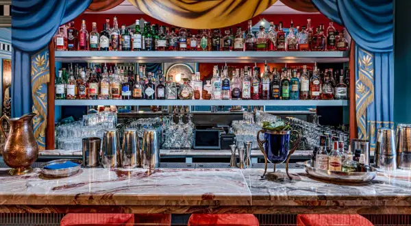 Un bar à cocktail élégant avec des étagères remplies de bouteilles d'alcool, des verres et des ustensiles de bar.