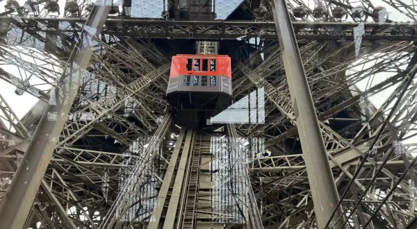 L'ascenseur rouge de la Tour Eiffel monte à travers la structure métallique complexe.