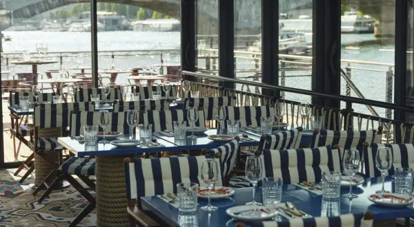 Tables dressées avec des rayures bleues et blanches, prêtes pour une "riviera fuga" sur la Seine.