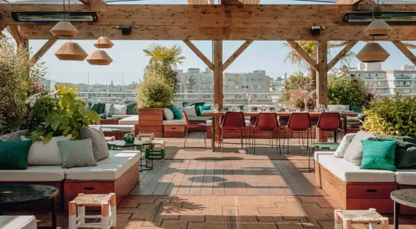 Ambiance chic et verdoyante sur le toit-terrasse du Perchoir Ménilmontant. Canapés confortables, tables dressées et vue panoramique sur Paris.