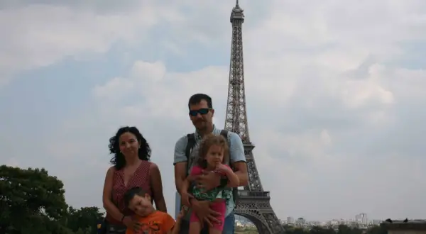 Famille souriante devant la Tour Eiffel, un classique des choses à faire à Paris avec des enfants.