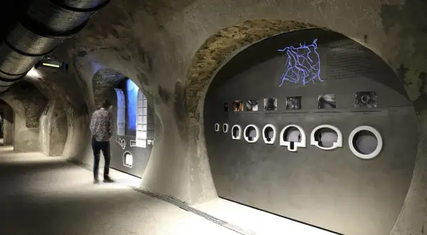 Visite du musée des égouts de Paris. Un visiteur observe une exposition sur le réseau d'assainissement, avec une carte lumineuse et des maquettes.