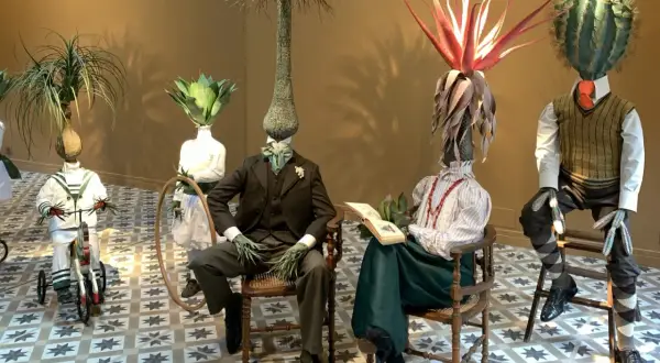 Mannequins aux têtes végétales dans l'espace Monte Cristo. Un enfant sur un tricycle, un couple lisant, un autre debout.