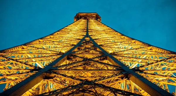 La Tour Eiffel illuminée d'une lumière dorée, comme une bougie géante, lors d'une visite nocturne à Paris.