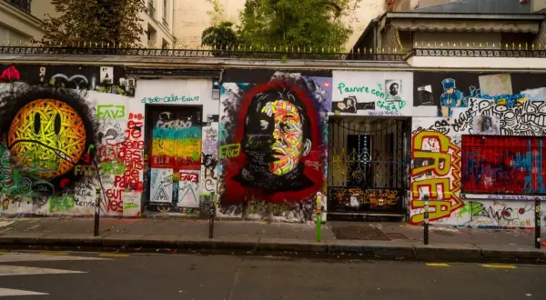 Mur couvert de graffitis colorés devant la maison Gainsbourg, avec un portrait de Serge Gainsbourg au centre.