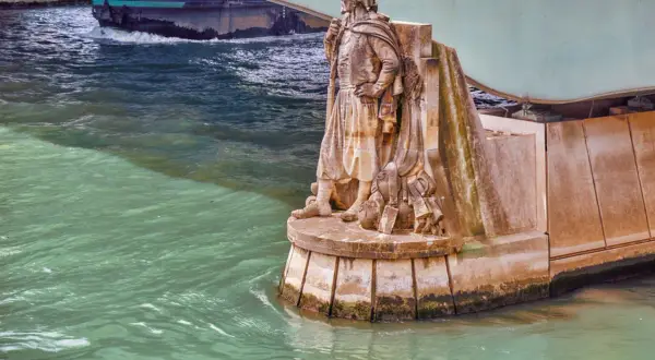 Statue de soldat sur le **pont de l'Alma**, regardant la Seine. Un bateau passe sous le pont.