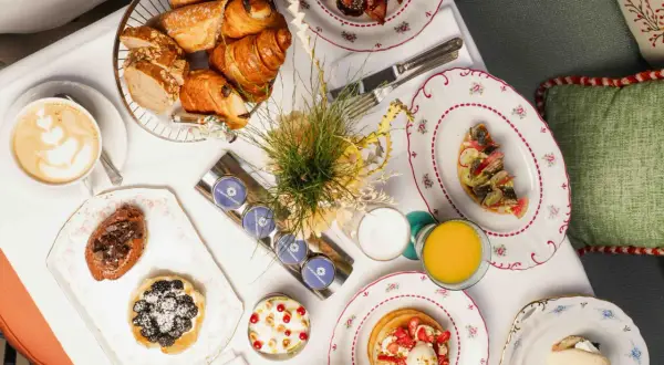 Un délicieux brunch parisien avec viennoiseries, tartines, pancakes aux fraises, et une tasse de café.