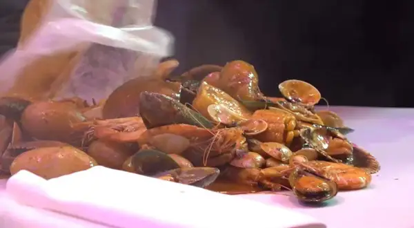 Un festin de fruits de mer à Paris : crevettes, moules et palourdes baignant dans une sauce savoureuse.