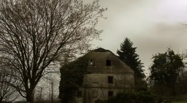 Une vieille maison abandonnée, envahie par la végétation, se dresse sous un ciel gris. On dirait une **maison hantée à Paris**, pleine de mystères.