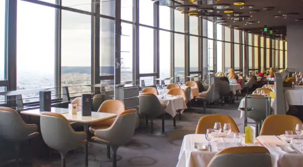 Vue panoramique depuis un restaurant du Tour Montparnasse à Paris. Tables dressées, vue sur la ville.