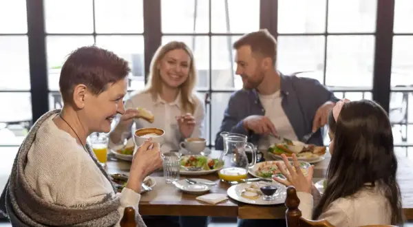 Une famille profite d'un repas joyeux dans un restaurant pour enfant. Grand-mère, parents et fille partagent un moment convivial autour d'une table garnie.