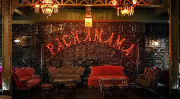 Ambiance feutrée au Pachamama Paris. Canapés vintage, luminaires scintillants et enseigne lumineuse pour un avis mémorable.