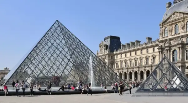 La pyramide du Louvre, un des musées ouverts le lundi, attire des visiteurs sous un ciel bleu.