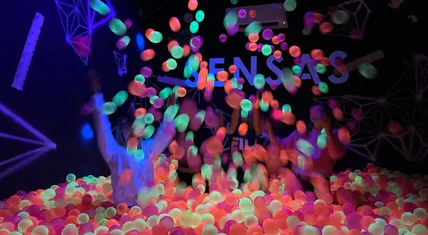 Des balles fluorescentes pleuvent sur des enfants dans une piscine à balles colorée. Une expérience sensas Paris inoubliable.