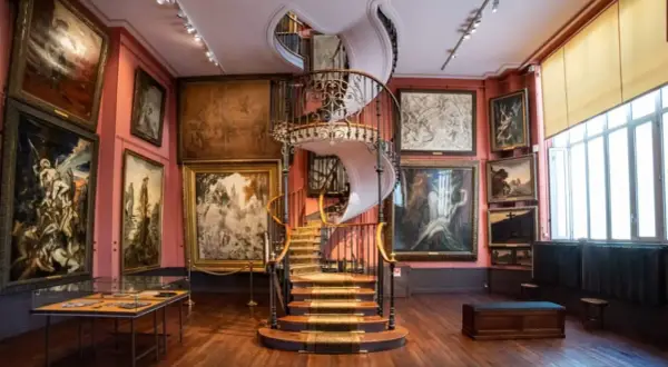 Escalier en colimaçon majestueux au cœur d'un musée insolite à Paris, entouré de tableaux sombres et évocateurs.