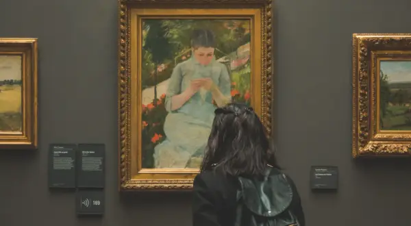 Une visite au musée gratuit premier dimanche du mois. Une jeune femme admire un tableau représentant une jeune fille tricotant dans un jardin.