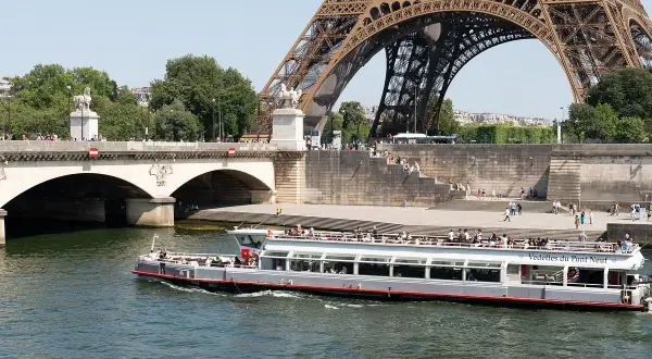 Les vedettes du Pont Neuf naviguent sur la Seine, sous la Tour Eiffel et le pont.