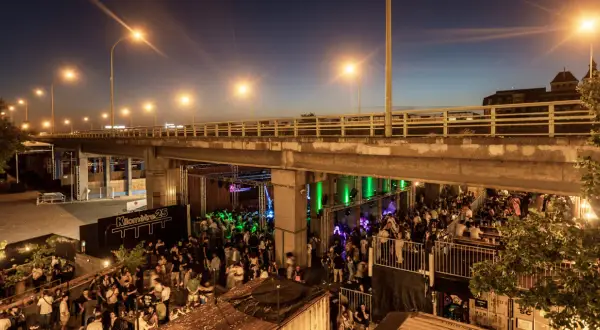 Soirée animée sous un pont, avec une foule dansant et profitant de la musique au Kilomètre 25.