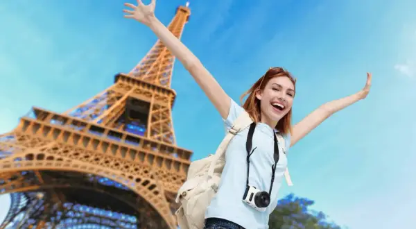 Joyeuse touriste avec appareil photo devant la Tour Eiffel. Un bon plan Paris pour des souvenirs inoubliables !