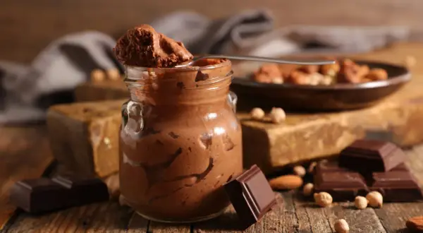 Une cuillère de mousse au chocolat parisienne, onctueuse et gourmande, sur fond de chocolat noir et noisettes.