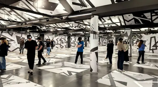 Des personnes équipées de casques VR explorent un espace immersif aux motifs graphiques noirs et blancs, une expérience unique à Eclipso Paris.