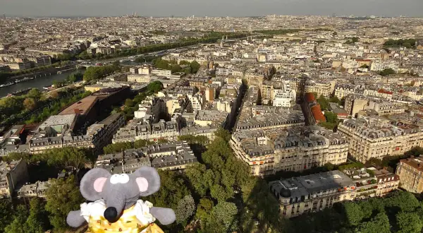 Une souris en robe jaune admire Paris depuis le sommet de la Tour Eiffel.