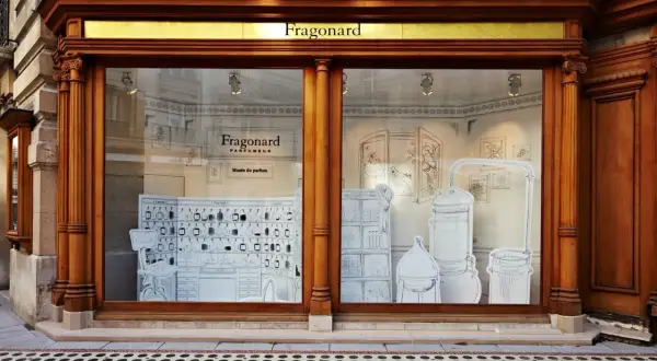 Vitrine du musée du parfum Fragonard, avec des illustrations de flacons, d'alambics et de mobilier d'apothicaire.