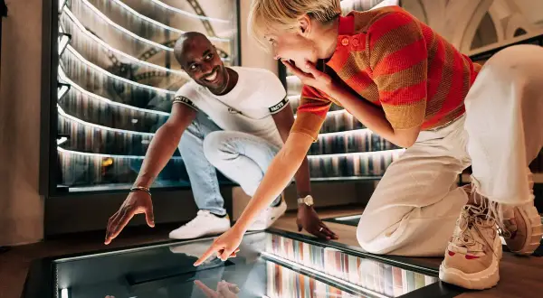 Un couple s'émerveille devant une installation interactive dans un musée des paradoxes.