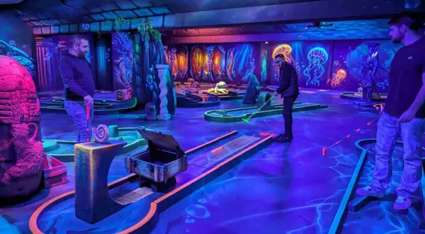 Ambiance sous-marine pour un escape game avec enfant. Parcours de mini-golf fluorescent, décoré de méduses et de dauphins, promettant une aventure ludique.