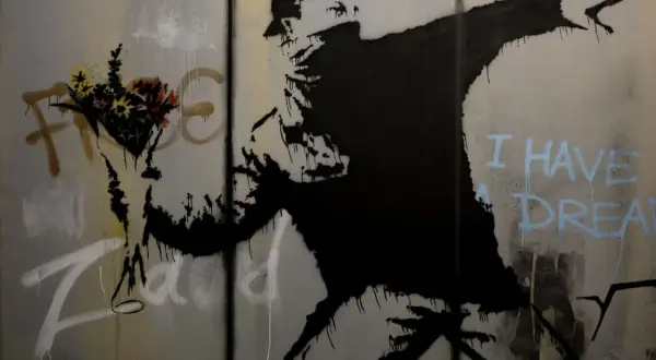 Un homme lance des fleurs, un message d'espoir du musée Banksy Paris. "I have a dream" écrit en bleu.