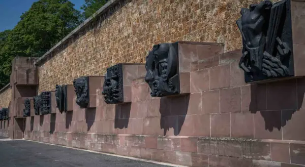 Sculptures sombres sur un mur de pierre à Mont Valérien, évoquant des figures humaines et animales dans un style dramatique.