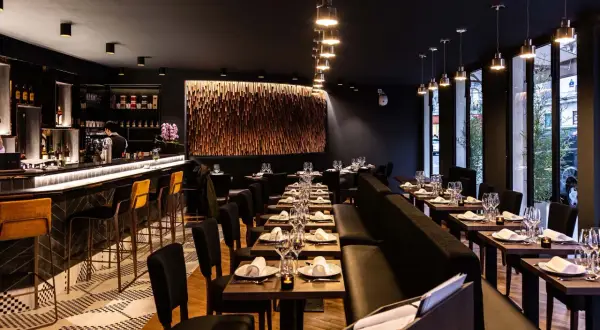 Ambiance chic d'un restaurant thaïlandais, avec un bar lumineux, des tables dressées et une décoration murale en bois.
