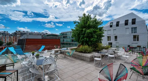 Terrasse ensoleillée avec chaises colorées et tables, un lieu idéal pour la maison de la conversation.