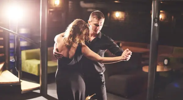Un couple danse passionnément lors d'une soirée dansante à Paris. L'homme en chemise noire enlace la femme en robe de soirée.