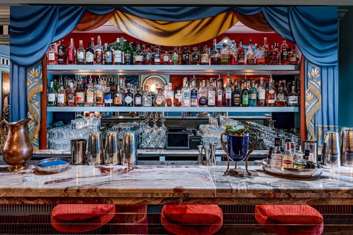 Un bar à cocktail élégant avec des étagères remplies de bouteilles d'alcool, des verres et des ustensiles de bar.