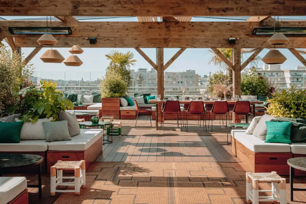 Ambiance chic et verdoyante sur le toit-terrasse du Perchoir Ménilmontant. Canapés confortables, tables dressées et vue panoramique sur Paris.