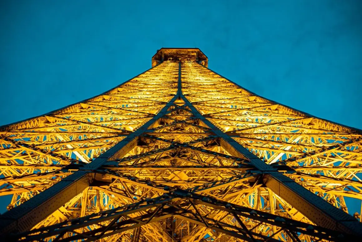 La Tour Eiffel illuminée d'une lumière dorée, comme une bougie géante, lors d'une visite nocturne à Paris.