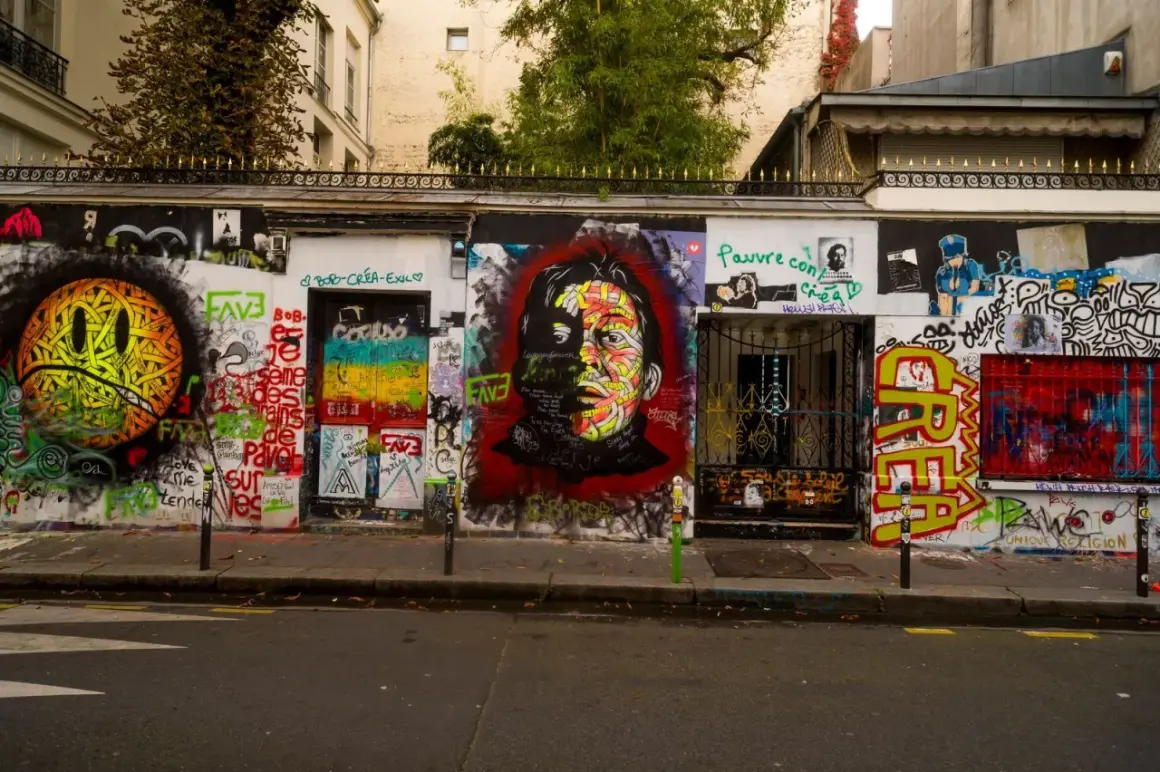 Mur couvert de graffitis colorés devant la maison Gainsbourg, avec un portrait de Serge Gainsbourg au centre.