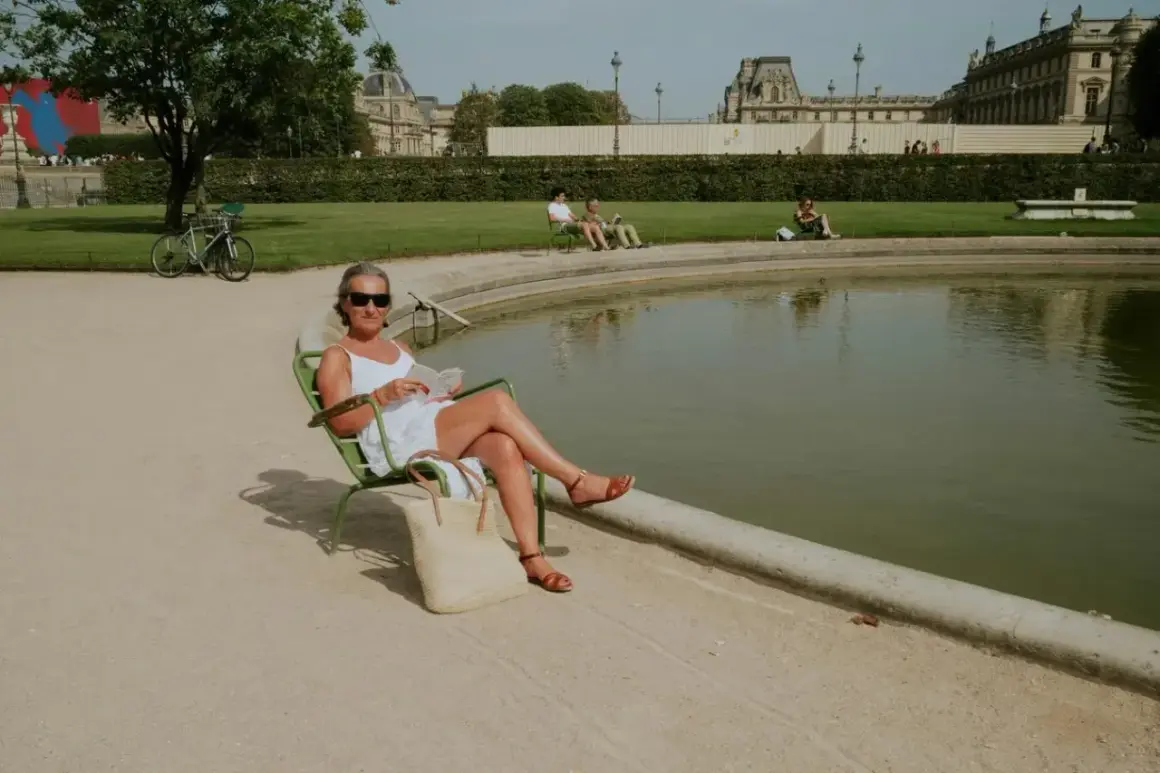Une femme lit au soleil, profitant d'un moment de détente pour ou bronzer à Paris, près d'un bassin.
