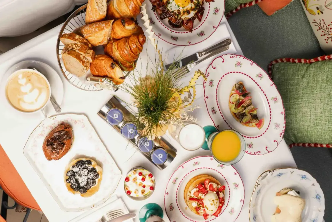 Un délicieux brunch parisien avec viennoiseries, tartines, pancakes aux fraises, et une tasse de café.