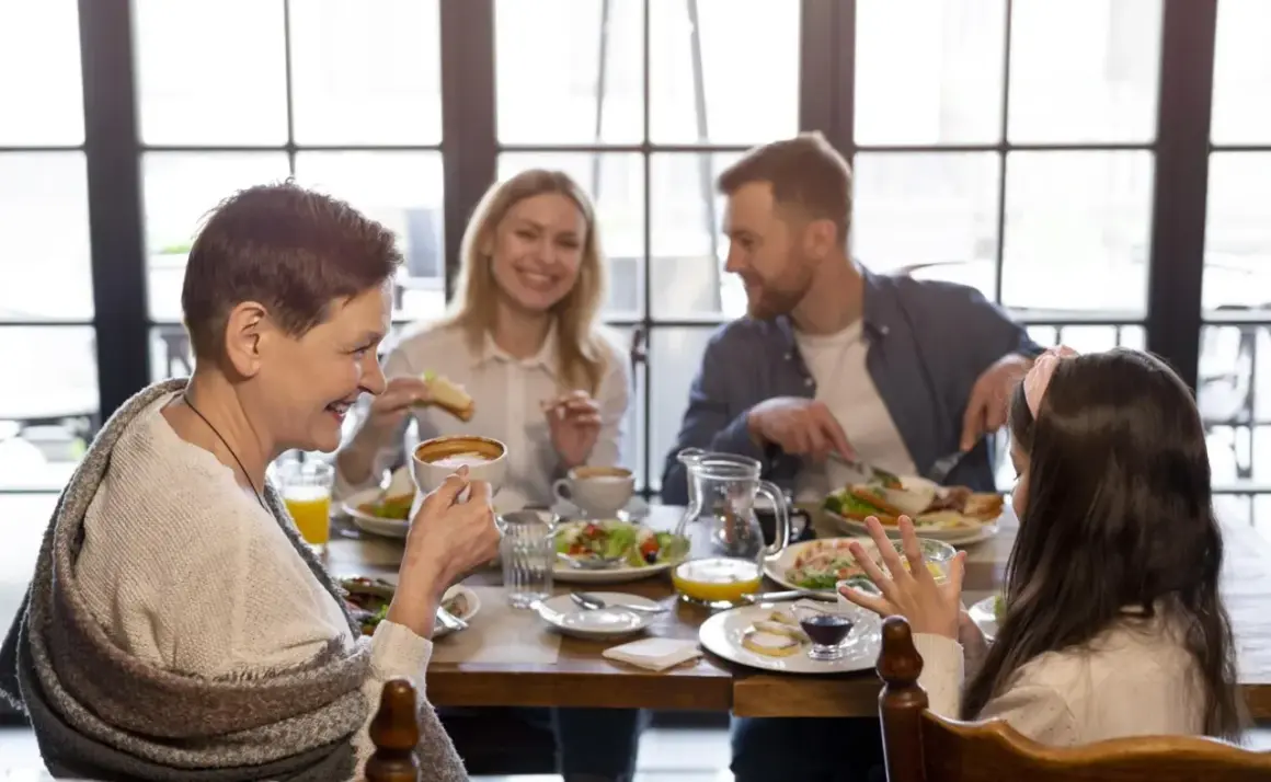 Une famille profite d'un repas joyeux dans un restaurant pour enfant. Grand-mère, parents et fille partagent un moment convivial autour d'une table garnie.