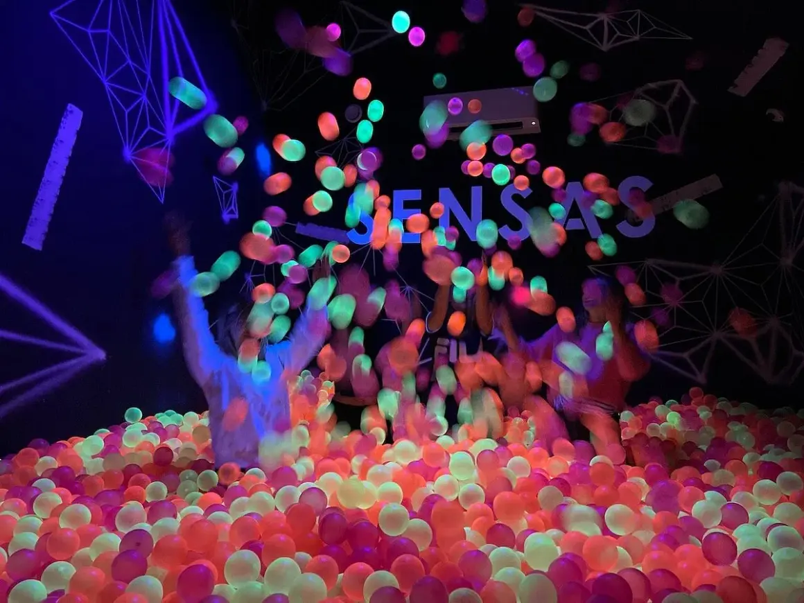 Des balles fluorescentes pleuvent sur des enfants dans une piscine à balles colorée. Une expérience sensas Paris inoubliable.