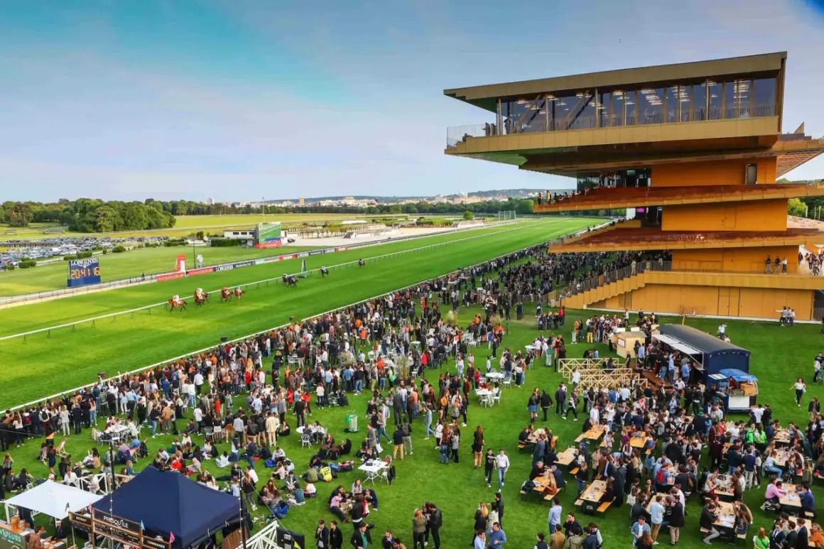 Ambiance festive à l'hippodrome de ParisLongchamp pour les jeuxdi. Une foule nombreuse profite de l'événement sur l'herbe, sous le soleil.