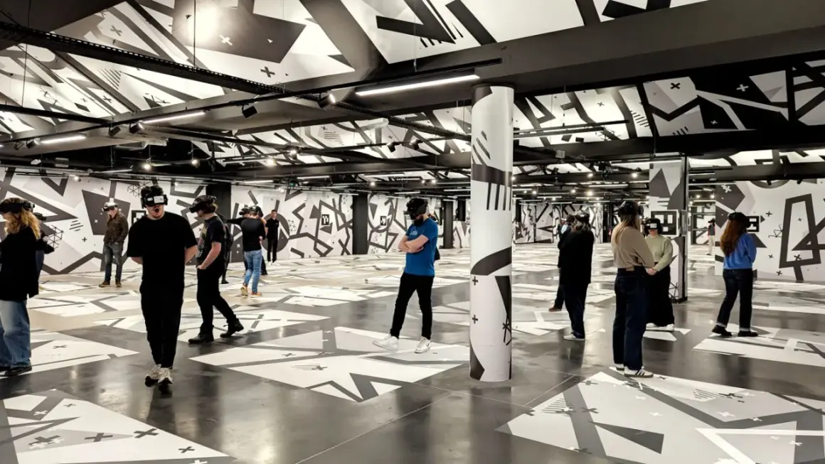 Des personnes équipées de casques VR explorent un espace immersif aux motifs graphiques noirs et blancs, une expérience unique à Eclipso Paris.